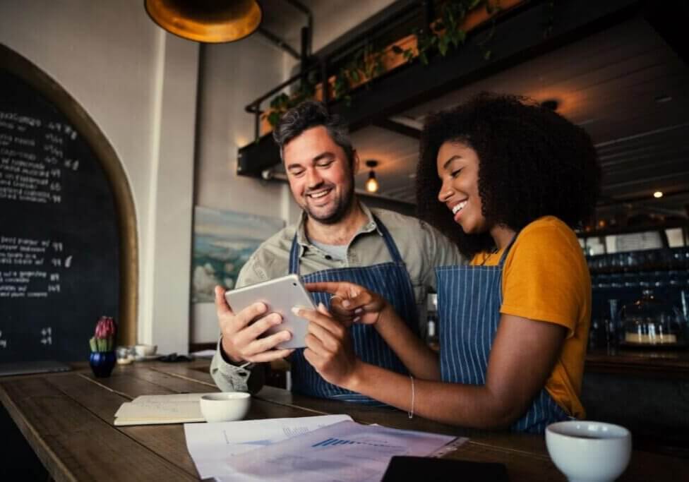 Manager and waitress looking at digital tablet standing in cafe