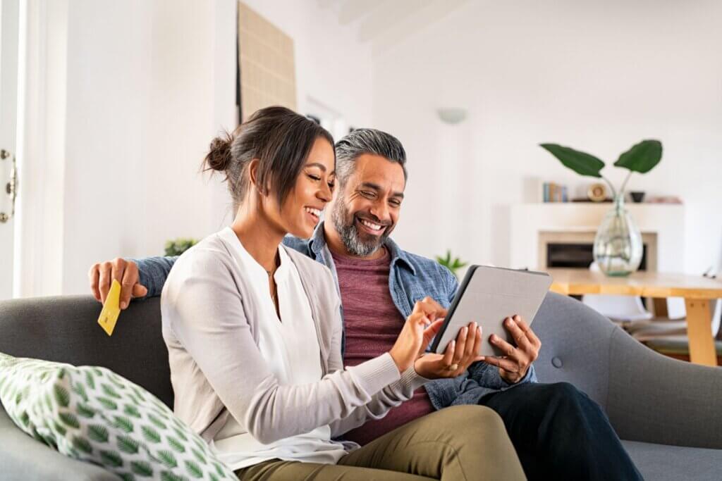 Happy mature couple using digital tablet for online payment.